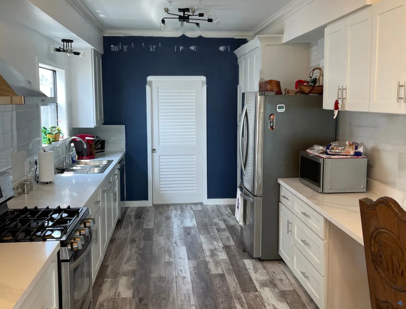 Completed MSS kitchen renovation with white shaker cabinets, stone counters, and a navy accent wall